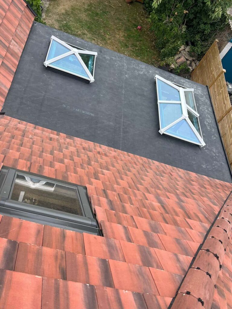 This is a photo taken from the roof ridge looking down a tiled pitched roof on to a flat roof. Works carried out by LJ Roofing Wantage